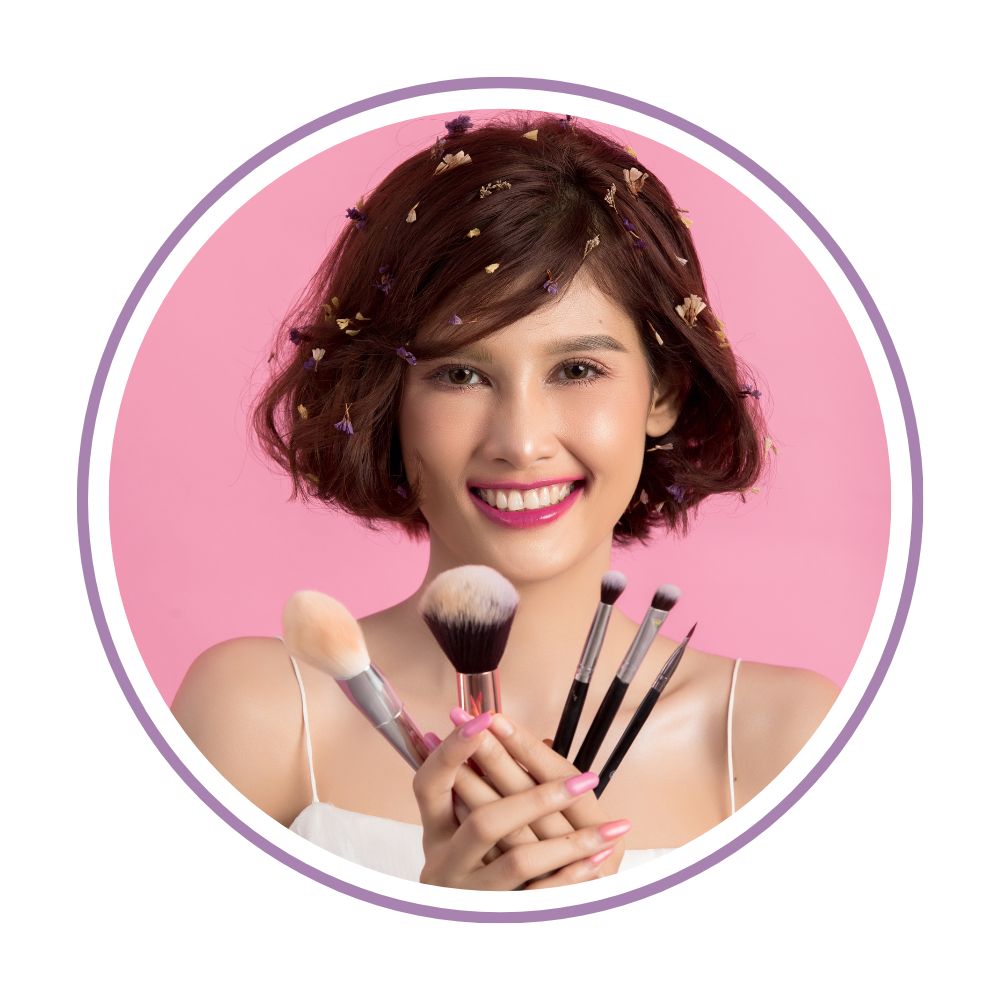 Smiling girl holding a set of professional makeup brushes on pink background